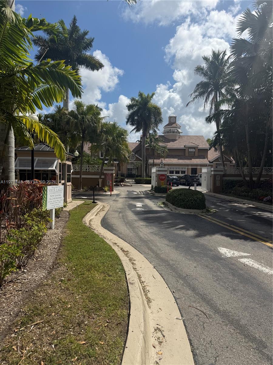 The entrance to the Vista Lago apartment complex features a gatehouse, palm trees, and road — 15680 SW 106th LN # 803, Miami FL 33196, MIAMI, FL