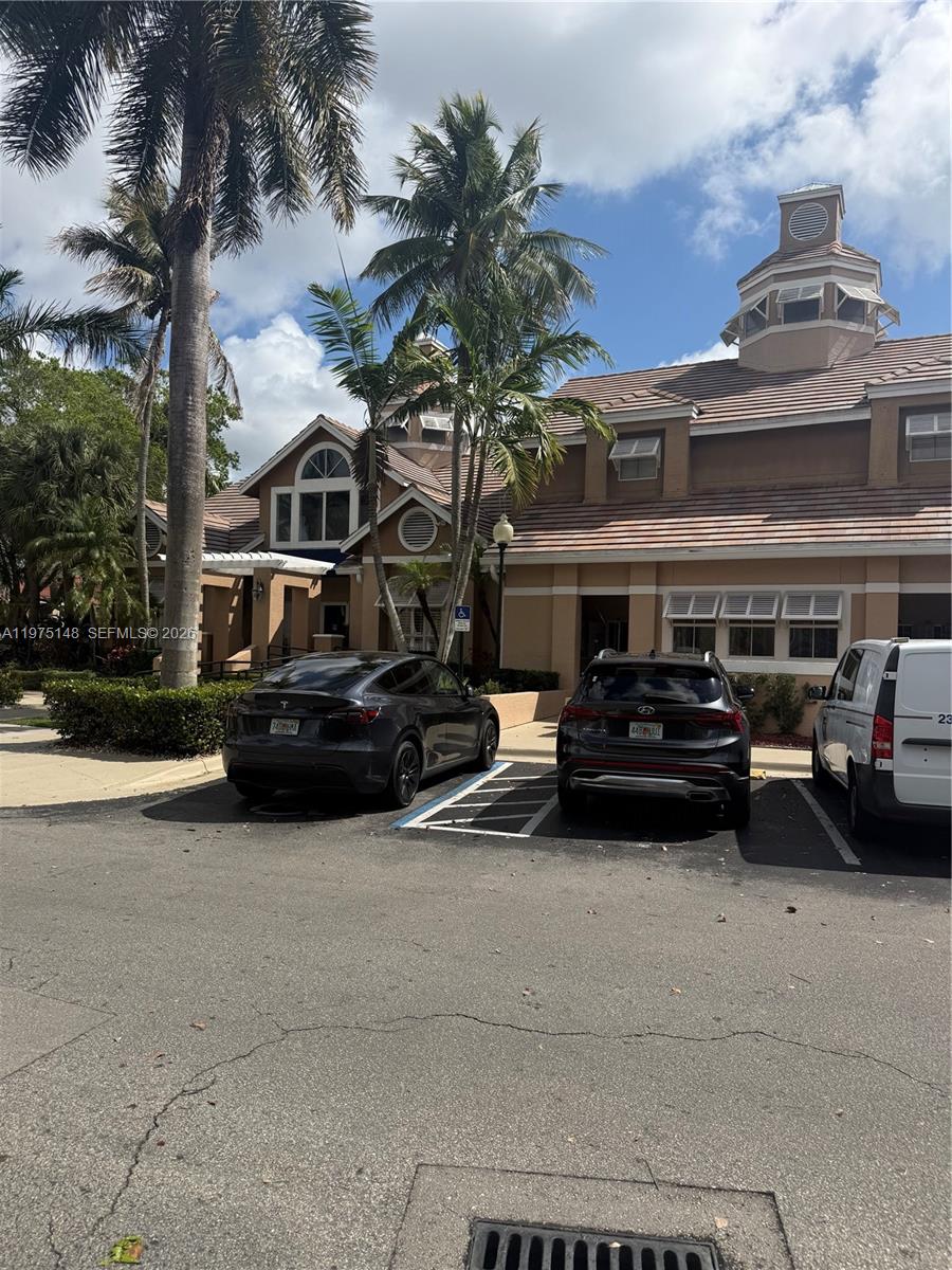 A parking lot sits in front of a tan building with a cupola and palm trees — 15680 SW 106th LN # 803, Miami FL 33196, MIAMI, FL