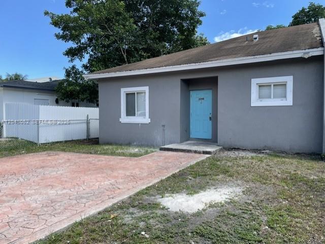 A gray single-story house features a bright blue front door and a stamped concrete driveway — 1240 NW 102nd St # 1240, Miami FL 33147, MIAMI, FL