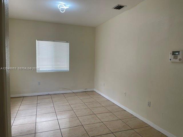 An empty room features beige walls, light-colored tile flooring, and a single window with blinds — 1240 NW 102nd St # 1240, Miami FL 33147, MIAMI, FL