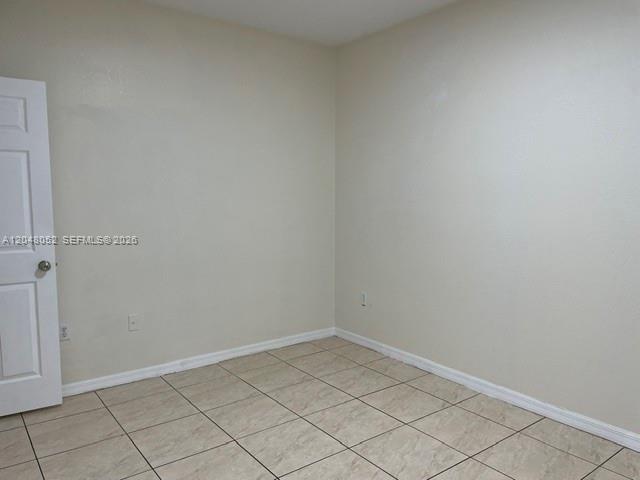 An empty room features beige walls, white trim, and light-colored square floor tiles — 1240 NW 102nd St # 1240, Miami FL 33147, MIAMI, FL