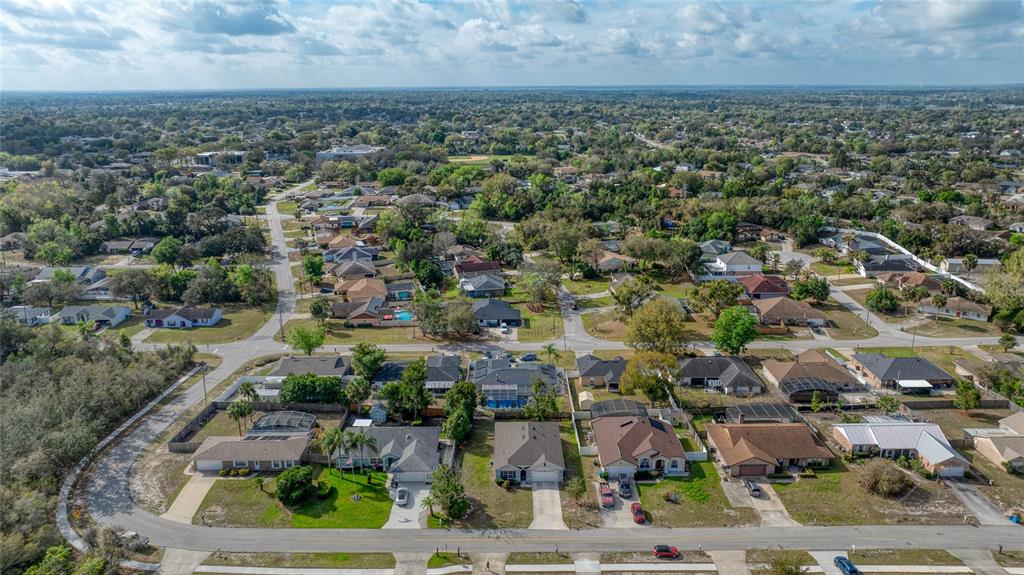 An aerial view shows a suburban neighborhood with single-family homes, paved streets, and green trees — 725 N FIRWOOD DRIVE, DELTONA, FL