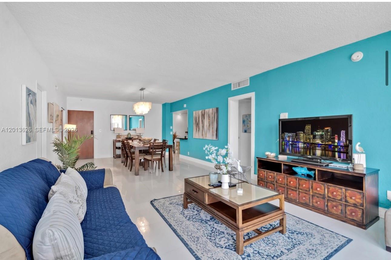 A living and dining room with a bright blue accent wall, tile floors, and wood furniture — 4001 S Ocean Dr # 7B, Hollywood FL 33019, HOLLYWOOD, FL