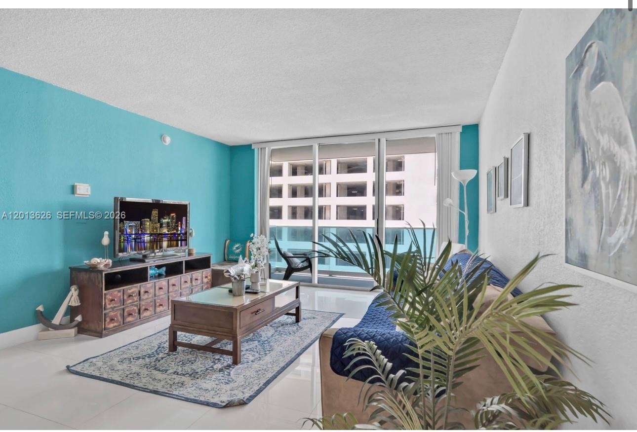 A living room features a turquoise accent wall, a wooden media console, and a balcony — 4001 S Ocean Dr # 7B, Hollywood FL 33019, HOLLYWOOD, FL