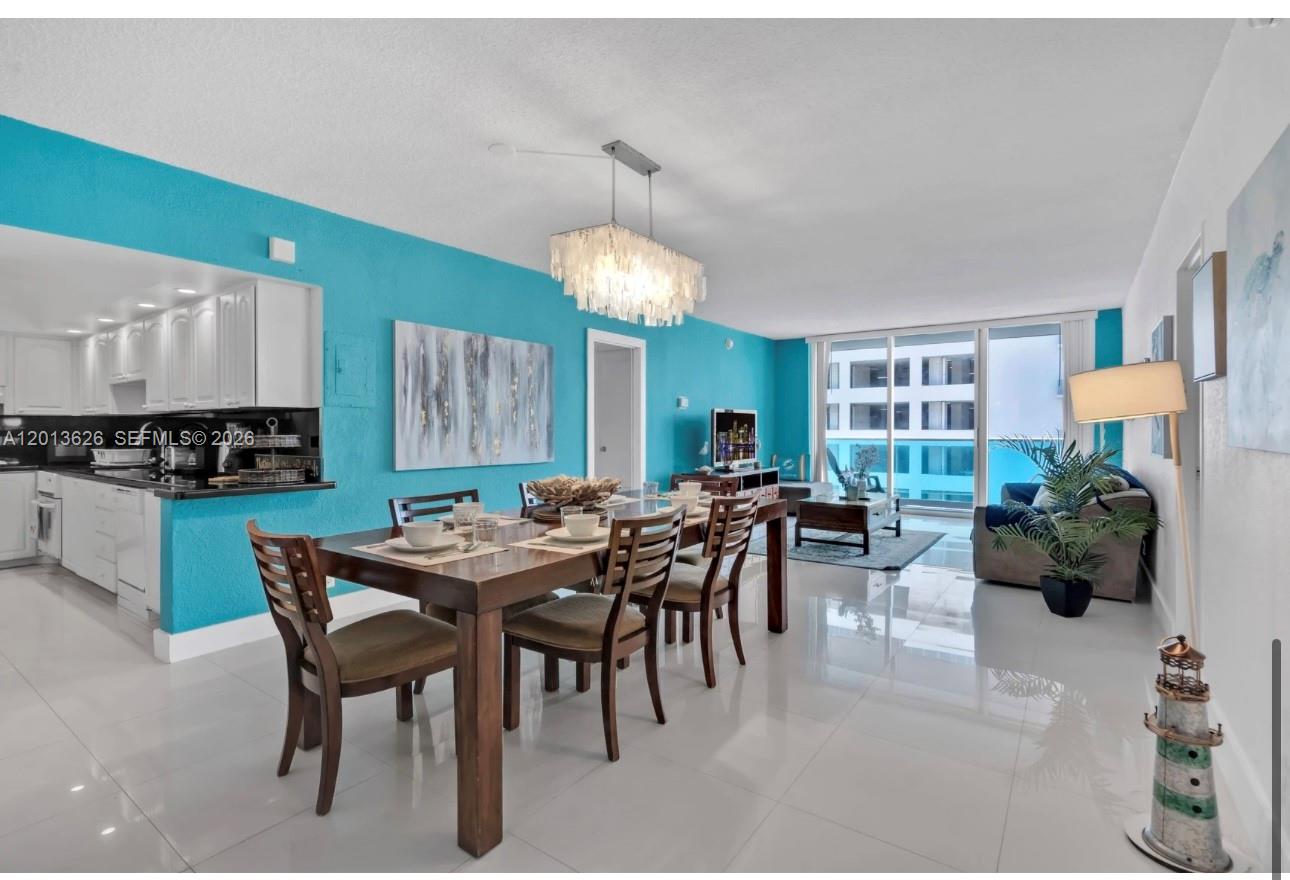 A dining area and living room with bright blue walls, tile floors, and modern lighting — 4001 S Ocean Dr # 7B, Hollywood FL 33019, HOLLYWOOD, FL