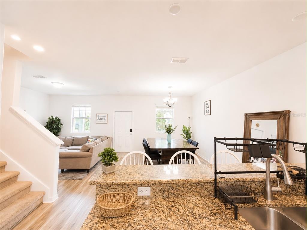 A kitchen island with granite countertops overlooks an open-concept living and dining area — 12820 STRODE LANE, WINDERMERE, FL