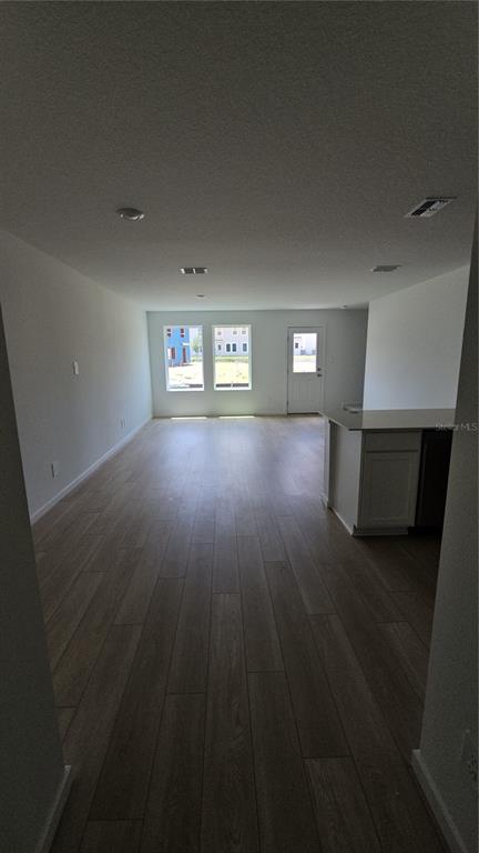 An open-concept living area features light wood-look flooring, white walls, and a kitchen island — 1230 ORION, DAVENPORT, FL