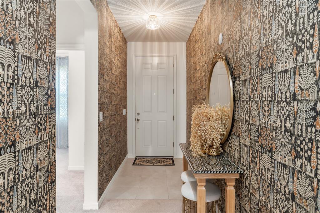 A narrow entryway features patterned wallpaper, a console table with a mirror, and a door — 1195 CRANE TALON WAY, SANFORD, FL