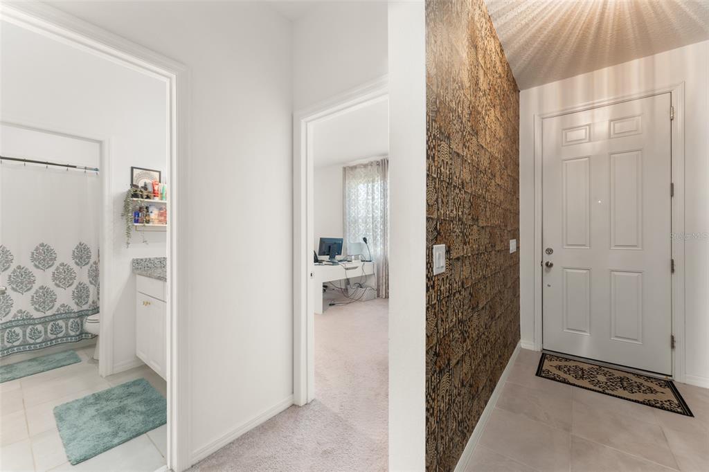 A hallway features a bathroom on the left, a bedroom ahead, and a patterned accent wall — 1195 CRANE TALON WAY, SANFORD, FL