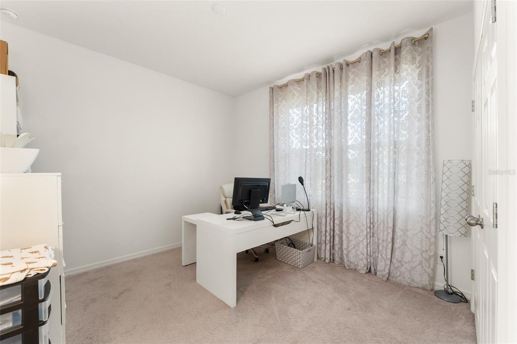 A home office features a white desk, beige carpet, and floor-to-ceiling curtains over a window — 1195 CRANE TALON WAY, SANFORD, FL