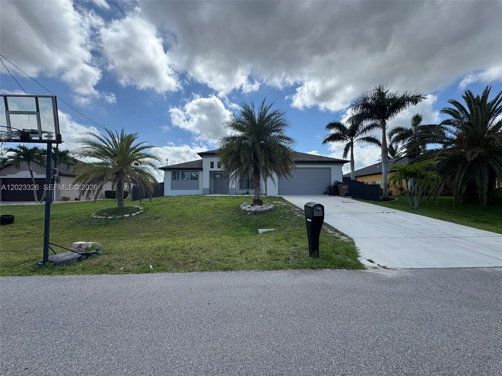 A single-story house with a concrete driveway, palm trees, and a basketball hoop in front — 113 NW 38th Pl, Cape Coral FL 33993, CAPE CORAL, FL
