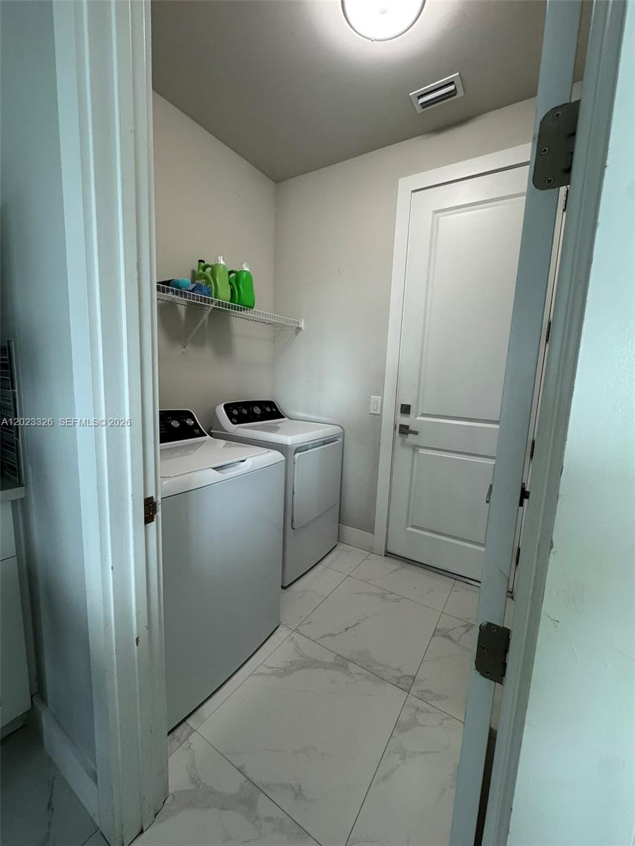 A laundry room features a white washer and dryer, a wire shelf, and light tile flooring — 113 NW 38th Pl, Cape Coral FL 33993, CAPE CORAL, FL