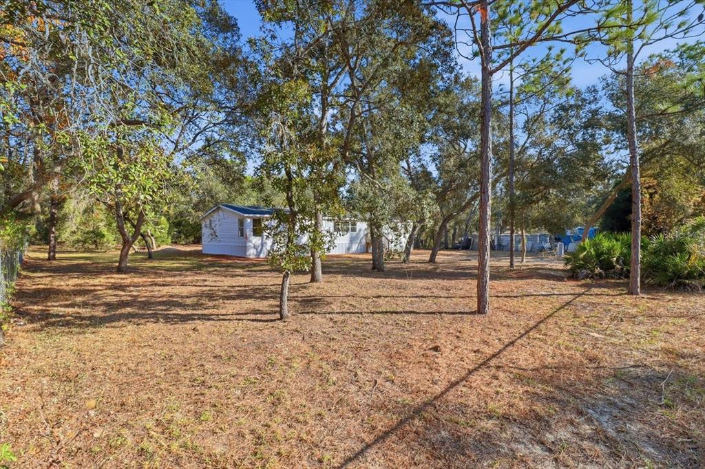 A white mobile home sits on a wooded lot with dry grass and tall trees — 5371 W WINTER SUN LANE, HOMOSASSA, FL