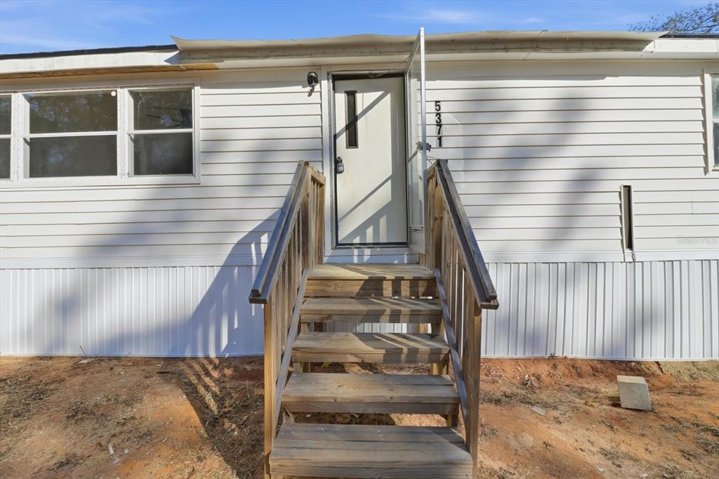 A wooden staircase leads to the front door of a white mobile home — 5371 W WINTER SUN LANE, HOMOSASSA, FL