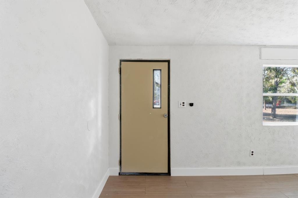 A room with white textured walls, wood-look flooring, and a tan door with a window — 5371 W WINTER SUN LANE, HOMOSASSA, FL
