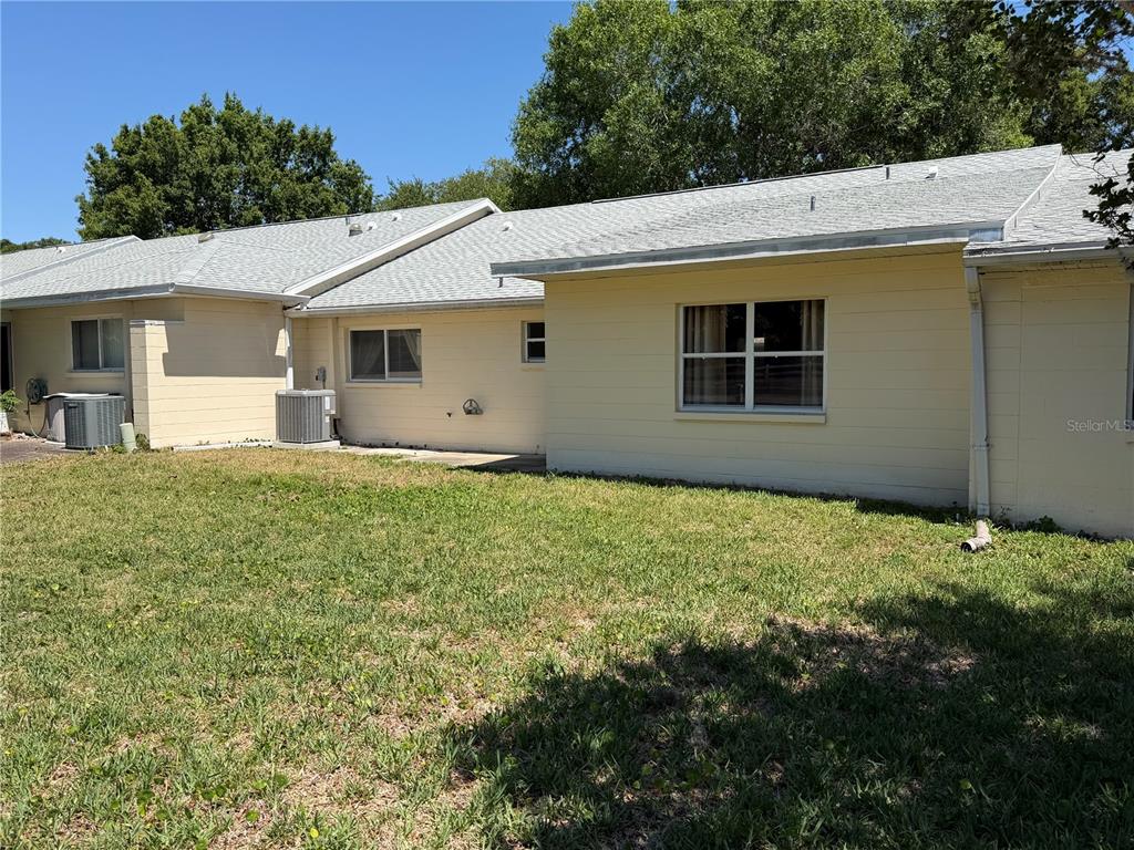 The exterior of a light-colored, single-story house features a grassy yard and two air-conditioning units — 9394 SW 97TH LANE UNIT B, OCALA, FL