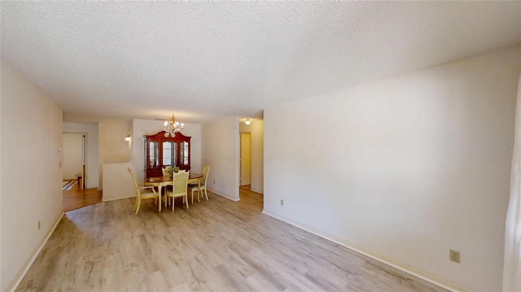 A dining area with a wooden hutch and table sits off a light-floored living room — 9394 SW 97TH LANE UNIT B, OCALA, FL