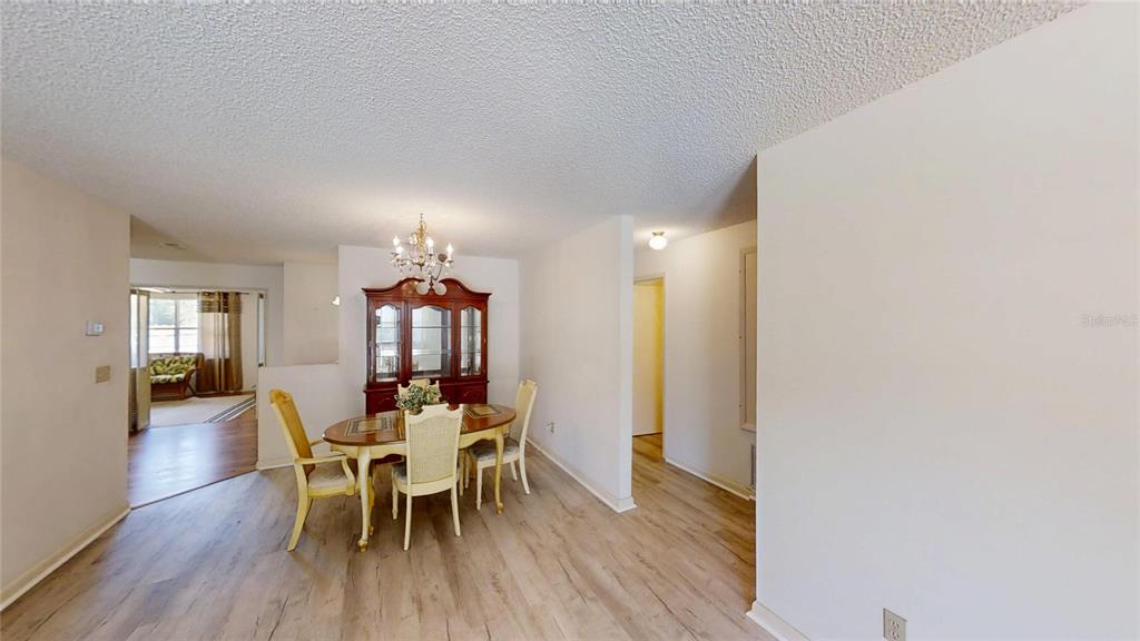A dining area features a wooden table, chairs, a hutch, and light-colored wood-look flooring — 9394 SW 97TH LANE UNIT B, OCALA, FL