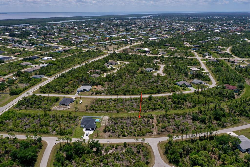 An aerial view shows a vacant residential lot marked with a red arrow — 8228 LEAFY WAY, PORT CHARLOTTE, FL