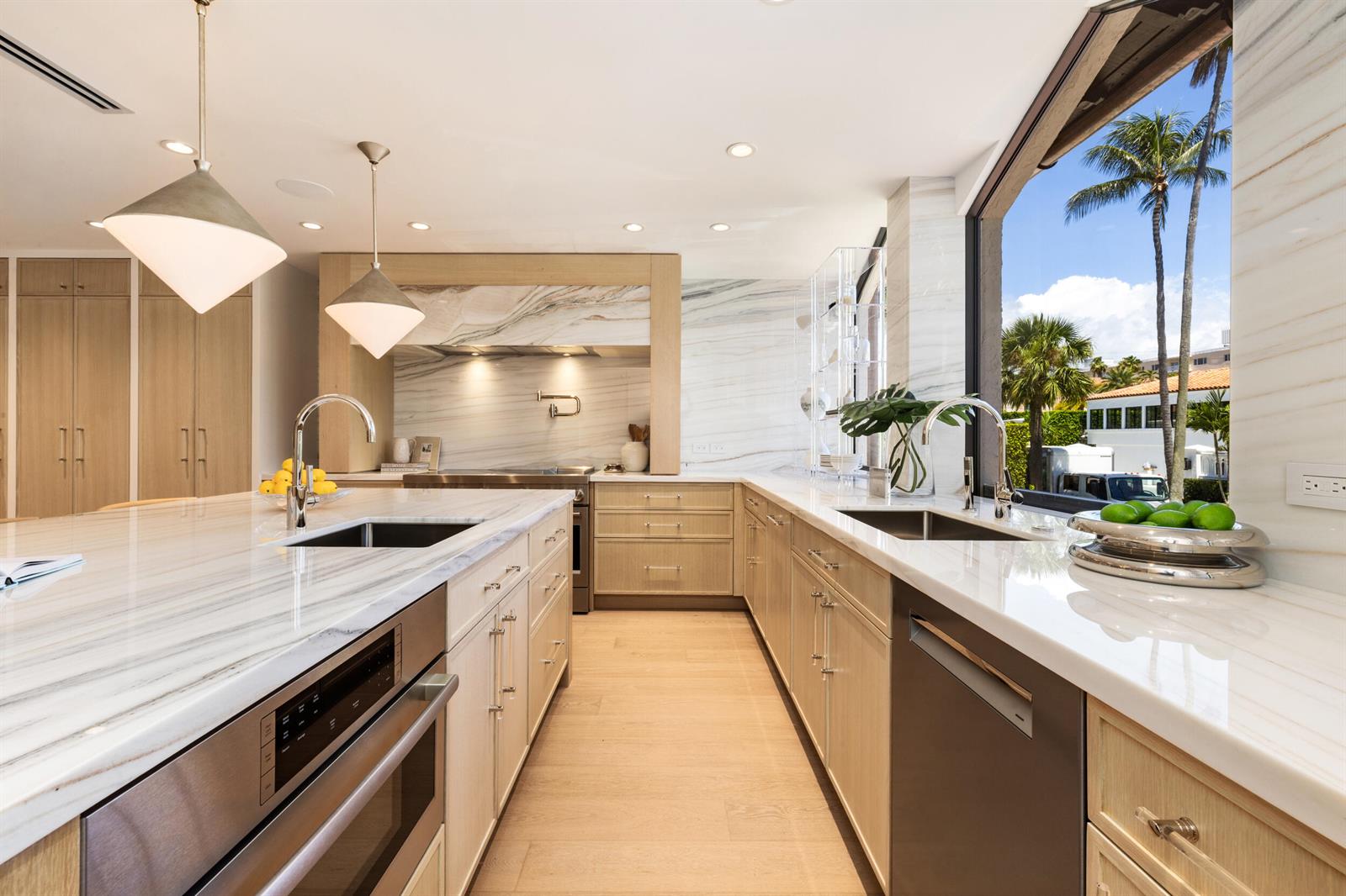 A modern kitchen features light wood cabinets, marble countertops, two sinks, and a large window — 260 Everglade Avenue, Palm Beach FL 33480, PALM BEACH, FL