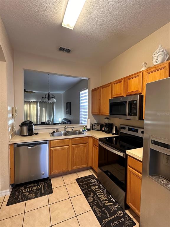 A kitchen features oak cabinets, stainless steel appliances, and a pass-through window to the living area — 141 LA MIRAGE STREET, DAVENPORT, FL