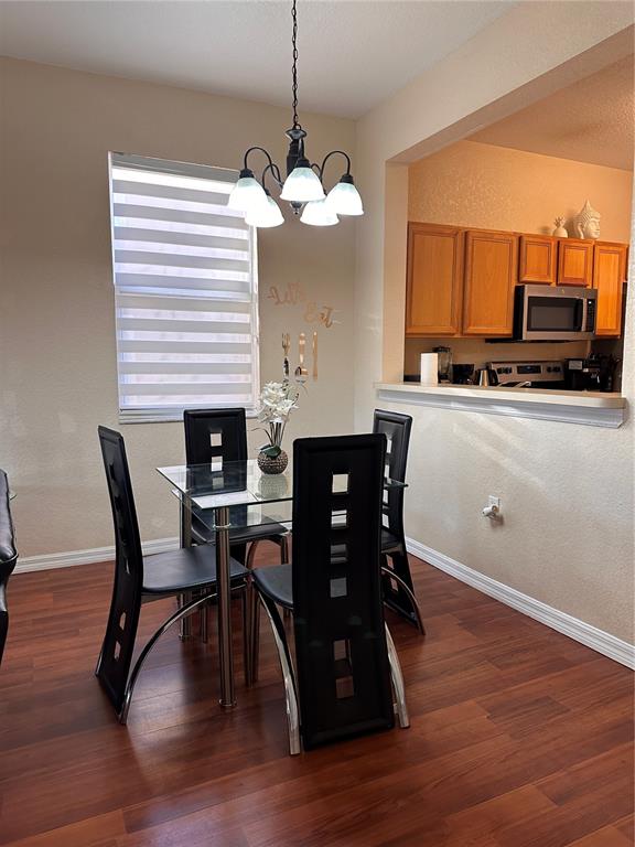 A dining area features a glass table, four black chairs, and a hanging light fixture — 141 LA MIRAGE STREET, DAVENPORT, FL