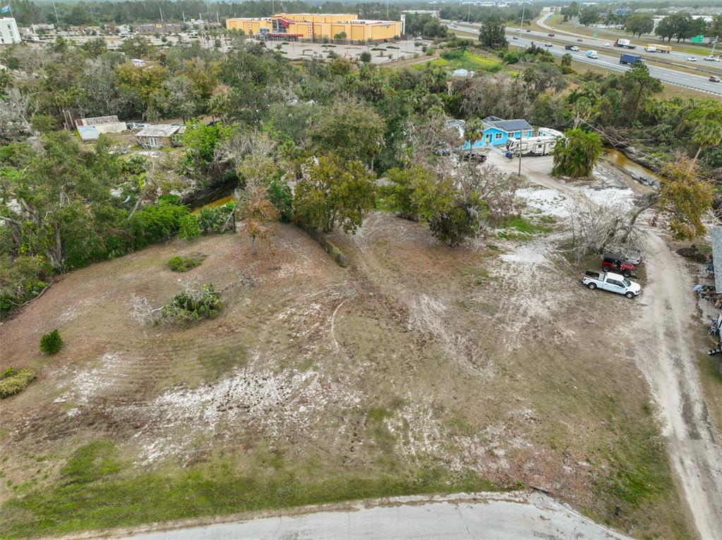 An aerial view shows a vacant, partially cleared lot with trees near a highway — 9423 BULLFROG COURT, GIBSONTON, FL