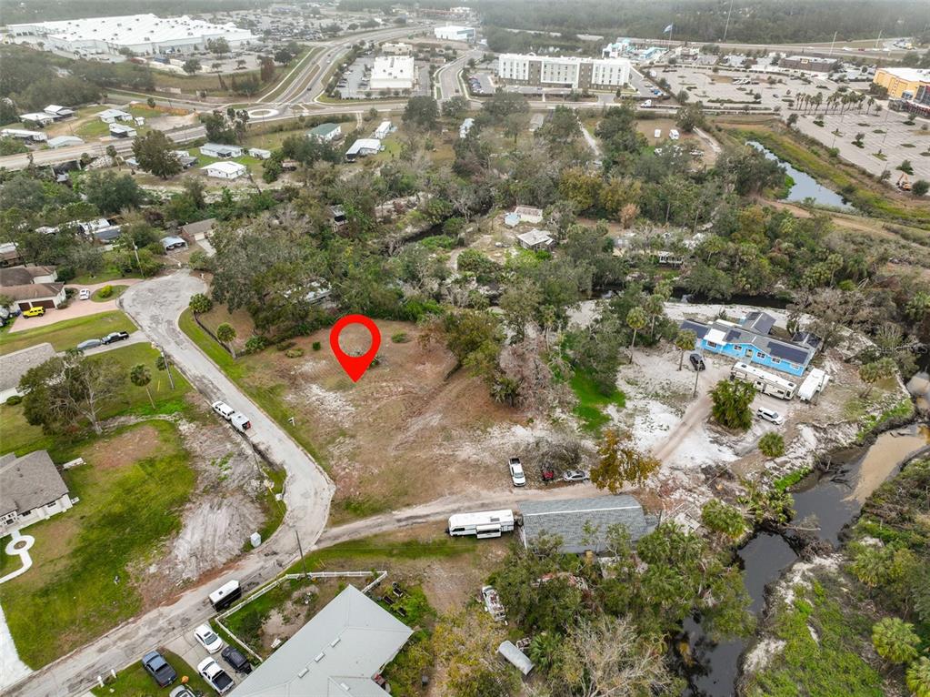 An aerial view shows a vacant, partially wooded lot marked with a red pin — 9423 BULLFROG COURT, GIBSONTON, FL