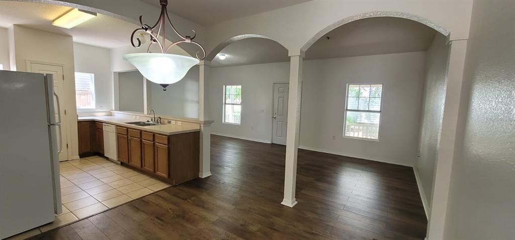 An open-concept kitchen with wood cabinets and tile floors transitions into a living area — 1004 PARK CENTRAL CIRCLE, GROVELAND, FL