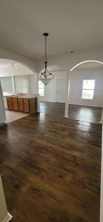 An open-concept dining area features wood-look flooring, a hanging light fixture, and arched doorways — 1004 PARK CENTRAL CIRCLE, GROVELAND, FL