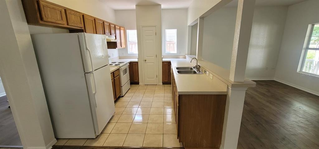 A kitchen with wood cabinets, white appliances, tile flooring, and a breakfast bar — 1004 PARK CENTRAL CIRCLE, GROVELAND, FL