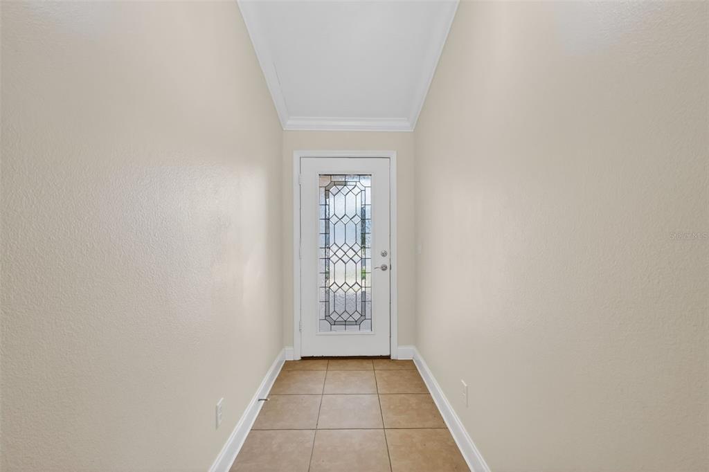 A narrow entryway features beige walls, a tiled floor, and a white door with glass — 4316 ABACO DRIVE, TAVARES, FL
