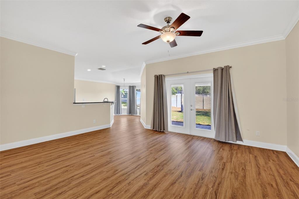 A living room with wood-look flooring, a ceiling fan, and glass doors leading outside — 4316 ABACO DRIVE, TAVARES, FL
