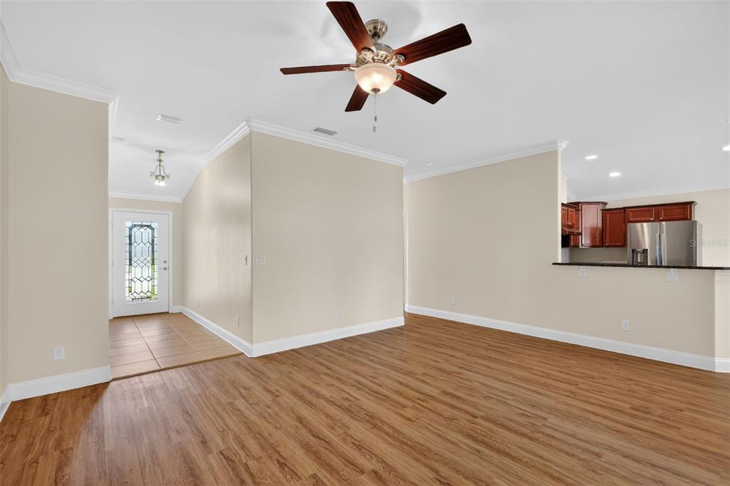 An open-concept living area features wood-look flooring, a ceiling fan, and an adjacent kitchen — 4316 ABACO DRIVE, TAVARES, FL