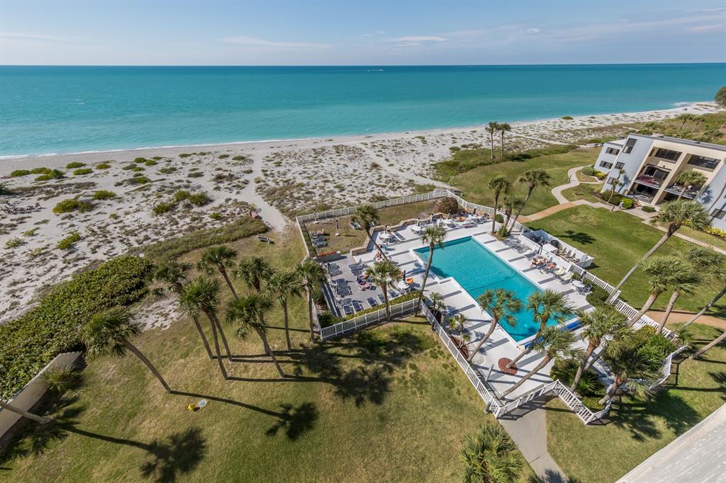 An aerial view shows a swimming pool and patio area next to a sandy beach — 700 GOLDEN BEACH BOULEVARD UNIT 236, VENICE, FL