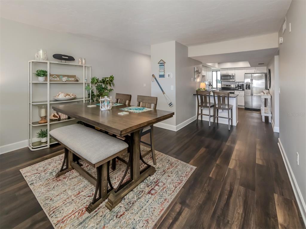 A dining area with a wooden table and bench sits adjacent to an open kitchen — 700 GOLDEN BEACH BOULEVARD UNIT 236, VENICE, FL