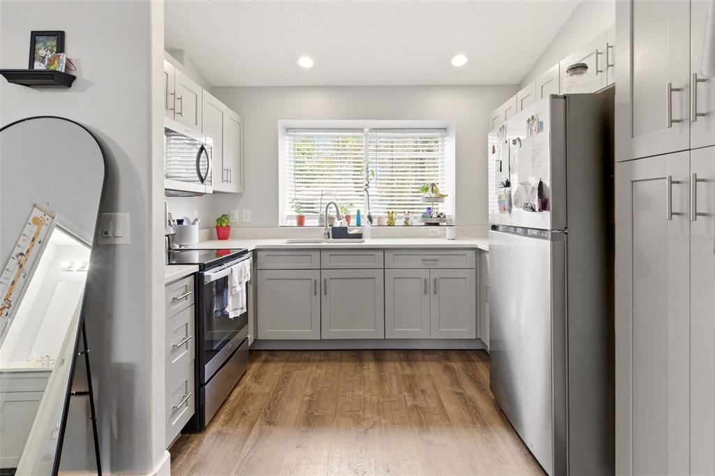 A kitchen features gray cabinets, stainless steel appliances, and wood-look flooring under a window — 1254 SANDESTIN WAY, ORLANDO, FL