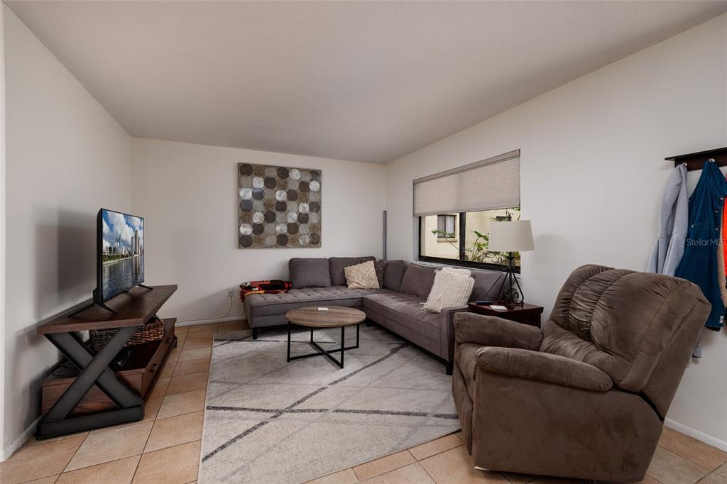 A living room features a sectional sofa, a recliner, a television, and tile flooring — 11708 RAINTREE VILLAGE BOULEVARD UNIT A, TEMPLE TERRACE, FL