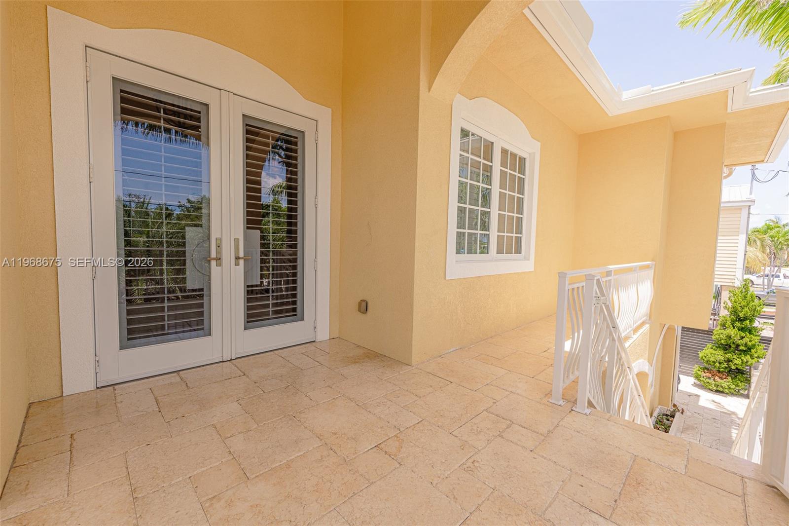 A tiled balcony features double glass doors, a window, and a white metal railing — 30825 Ortega Ln, Big Pine FL 33043, BIG PINE, FL