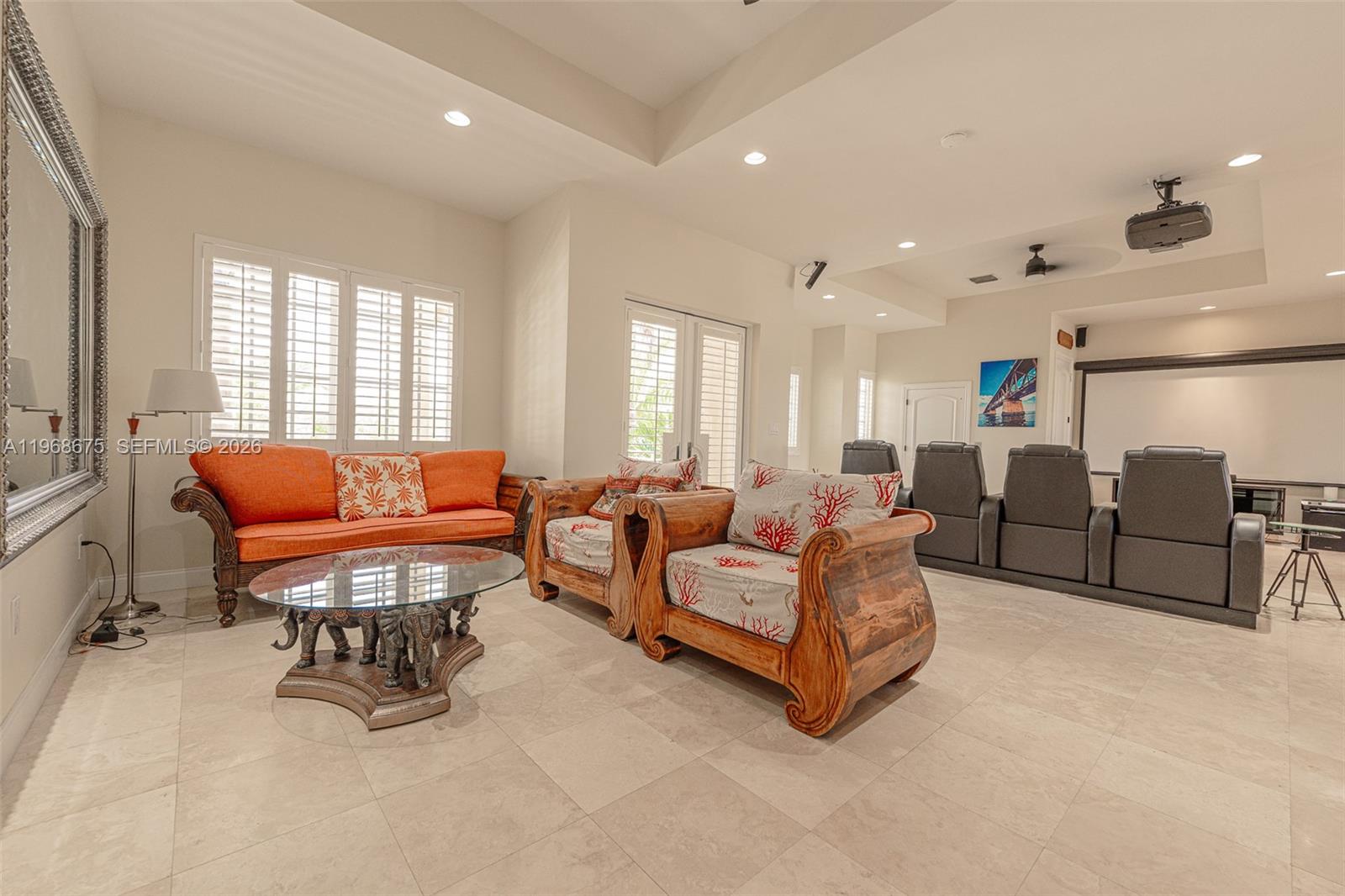 A living room features a wooden coffee table, orange sofa, armchairs, and a home theater screen — 30825 Ortega Ln, Big Pine FL 33043, BIG PINE, FL