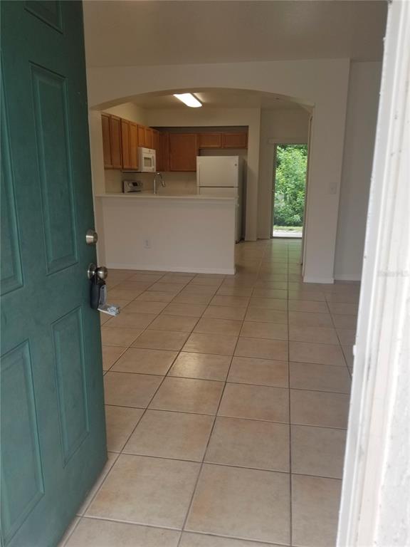 An open-concept kitchen with light-colored cabinets and tile flooring is viewed from an entryway — 6116 OLIVEDALE DRIVE, RIVERVIEW, FL