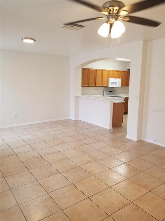 An open-concept living area features tiled floors, a ceiling fan, and an arched kitchen pass-through — 6116 OLIVEDALE DRIVE, RIVERVIEW, FL