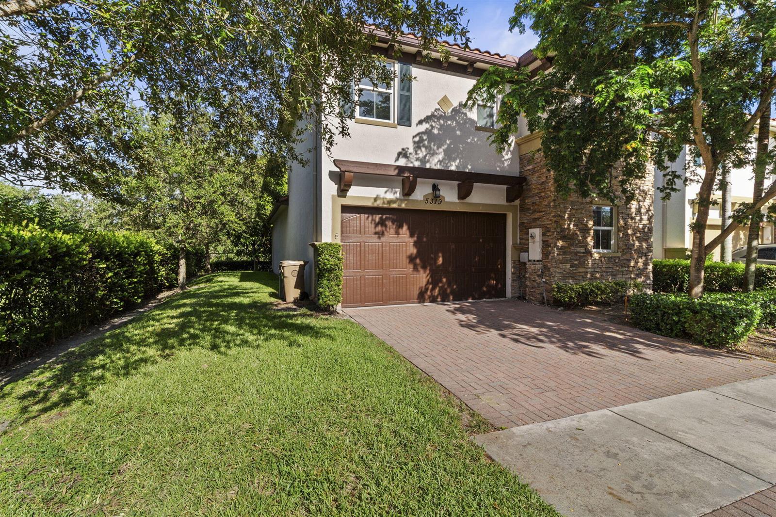 A two-story house with a brown garage door, stone accents, and a brick driveway — 5319 Falcon Trail, Davie FL 33314, DAVIE, FL