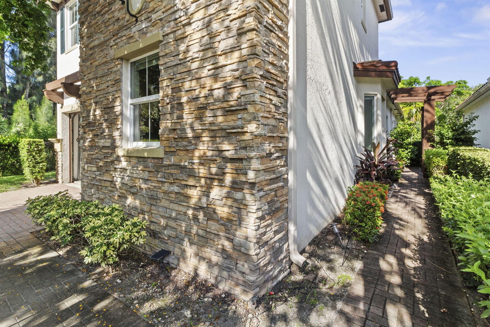 A stone-veneer exterior wall features a window and a paved walkway along the side yard — 5319 Falcon Trail, Davie FL 33314, DAVIE, FL