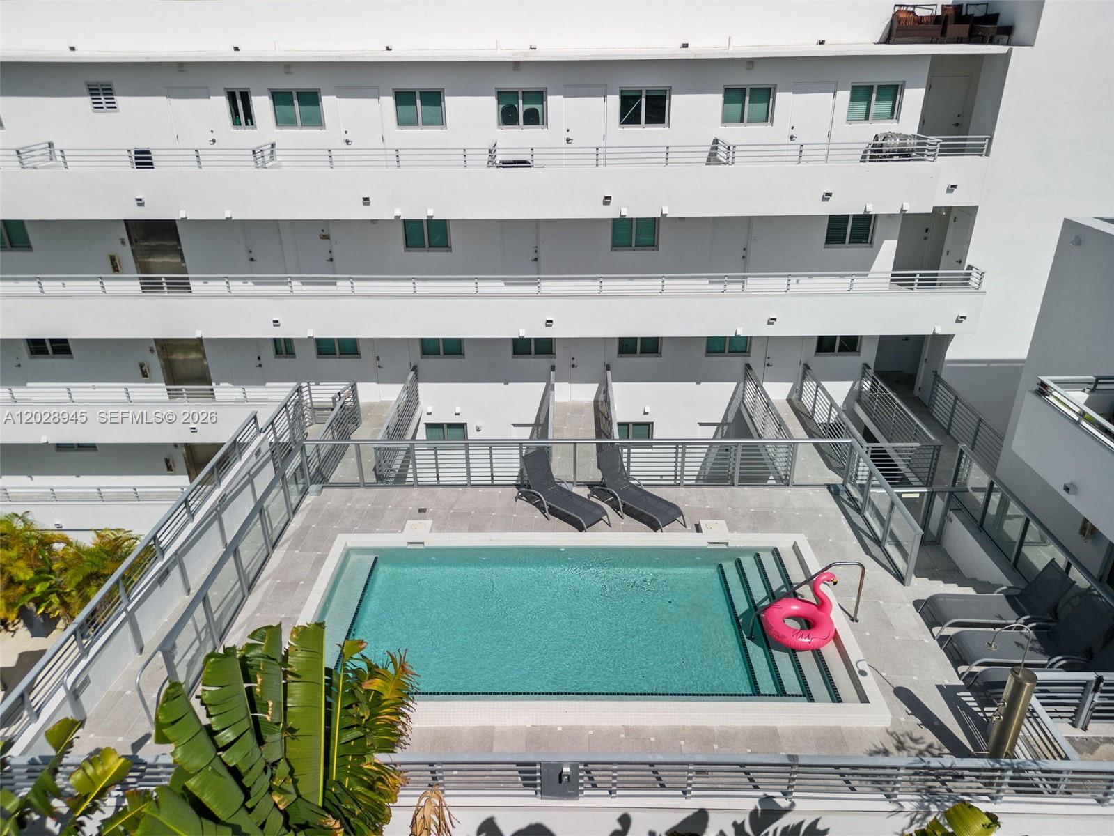 An aerial view shows a rectangular swimming pool with a pink float on a patio — 421 Meridian Ave # 6, Miami Beach FL 33139, MIAMI BEACH, FL