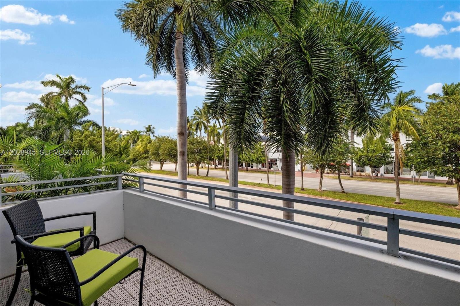 A balcony with two chairs overlooks a street lined with palm trees and buildings — 421 Meridian Ave # 6, Miami Beach FL 33139, MIAMI BEACH, FL