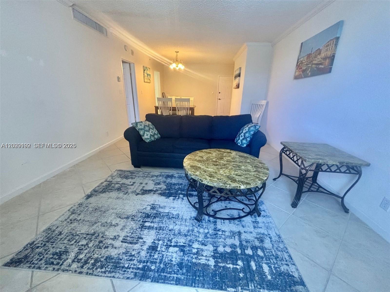 A living room features a blue sofa, a round marble coffee table, and tile flooring — 2501 S Ocean Dr # 433, Hollywood FL 33019, HOLLYWOOD, FL