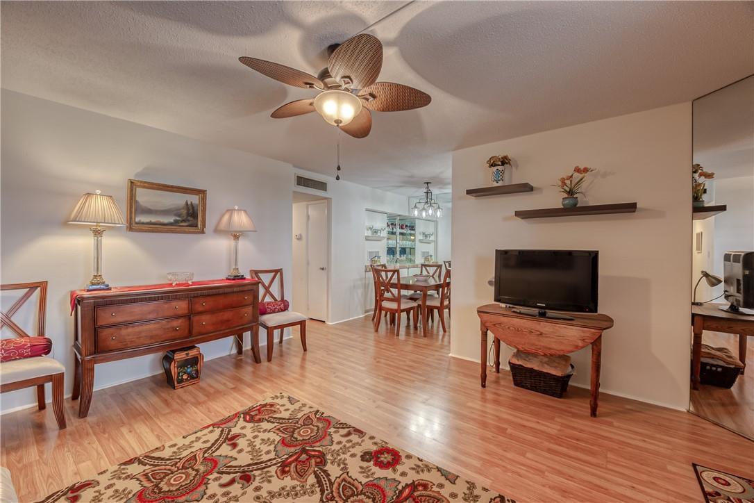 A living room features wood-look flooring, a ceiling fan, a television, and a dining area — 2400 NE 10th Street # 204, Pompano Beach FL 33062, POMPANO BEACH, FL
