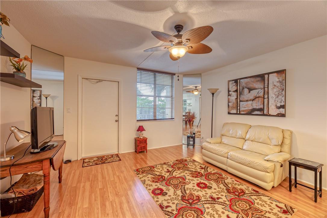 A living room with wood-look flooring, a beige sofa, a patterned rug, and ceiling fan — 2400 NE 10th Street # 204, Pompano Beach FL 33062, POMPANO BEACH, FL