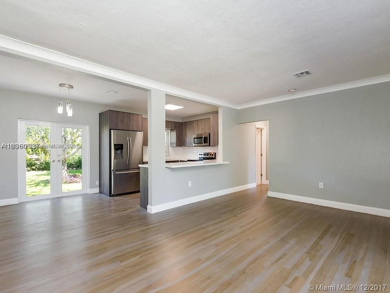 A living area with light wood floors opens to a kitchen featuring stainless steel appliances — 1231 N 16th Ct, Hollywood FL 33020, HOLLYWOOD, FL